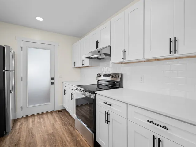a kitchen with stainless steel appliances white cabinets and a stove top oven