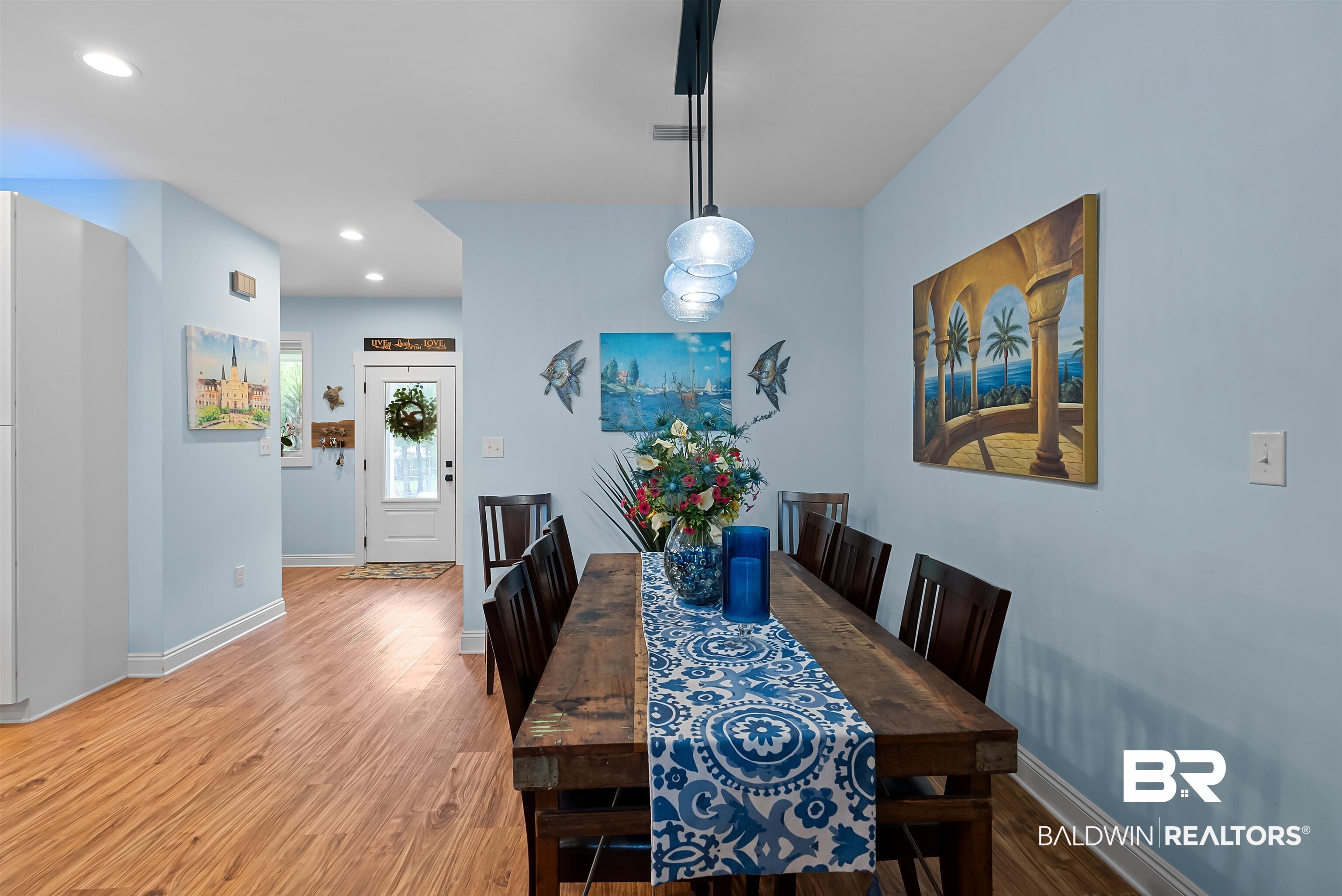 7266 Franklin Road Foley, AL 36535 - Photo 20 of 64 Dining area featuring wood-finish flooring, a linear pendant light fixture with blue glass shades, and light blue walls