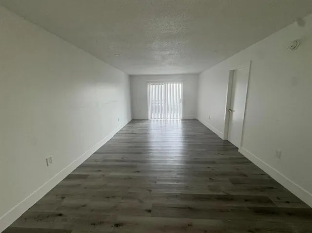 a view of an empty room with wooden floor and window
