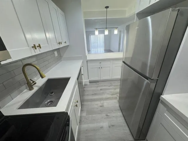 a view of a kitchen with fridge and wooden floor