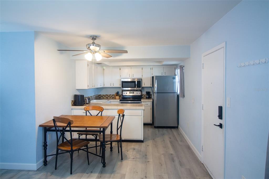 400 Base, Unit 225 Venice, FL 34285 - Photo 3 of 20 a kitchen with stainless steel appliances a dining table chairs refrigerator and cabinets