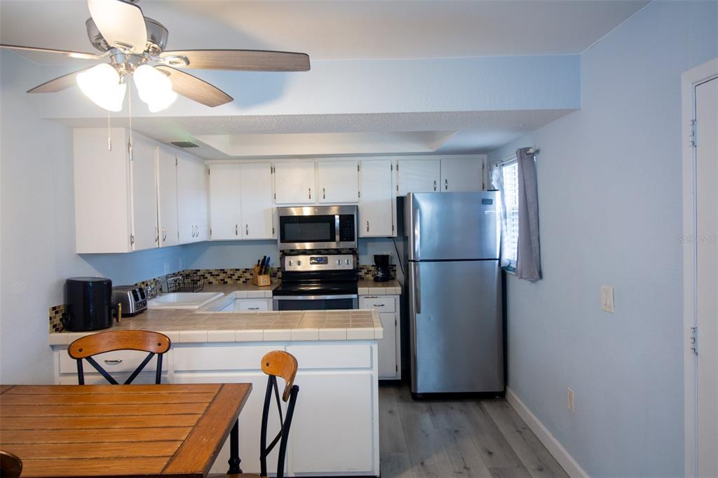 400 Base, Unit 225 Venice, FL 34285 - Photo 4 of 20 a kitchen with stainless steel appliances a refrigerator a sink a stove a dining table and chairs