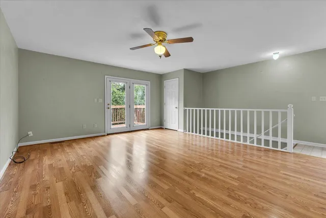 a view of an empty room with wooden floor and window