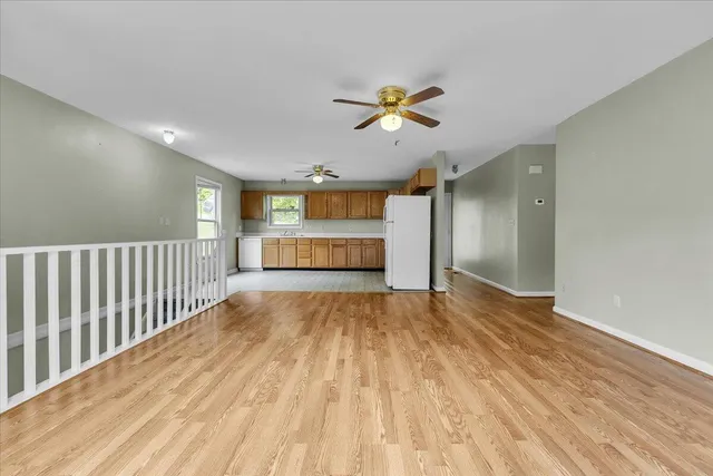a view of empty room with wooden floor and ceiling fan