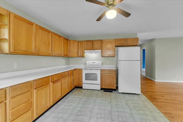 an empty room with windows and chandelier fan