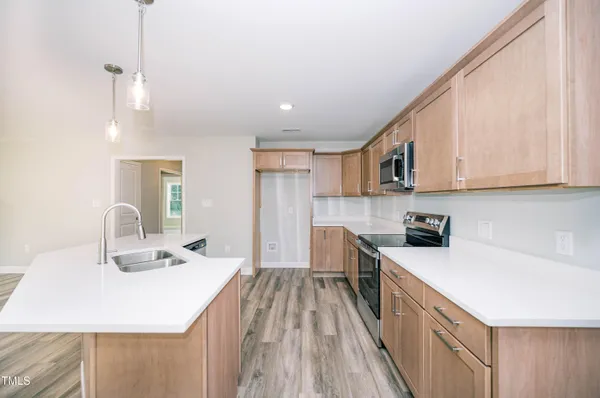 a kitchen with stainless steel appliances a sink a stove a refrigerator cabinets and a window