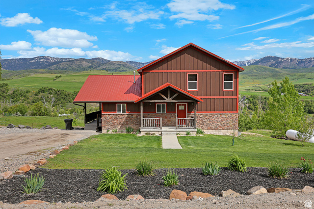 306 Spring Road Preston, ID 83263 - Photo 49 of 55 Two-story residence featuring a striking red metal roof, brown vertical siding, and a stone-clad foundation