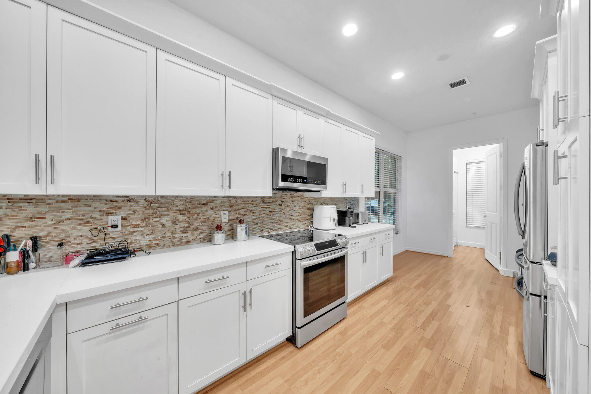 23008 Clear Echo Drive, Unit 11 Boca Raton, FL 33433 - Photo 5 of 64 a kitchen with white cabinets sink and stainless steel appliances
