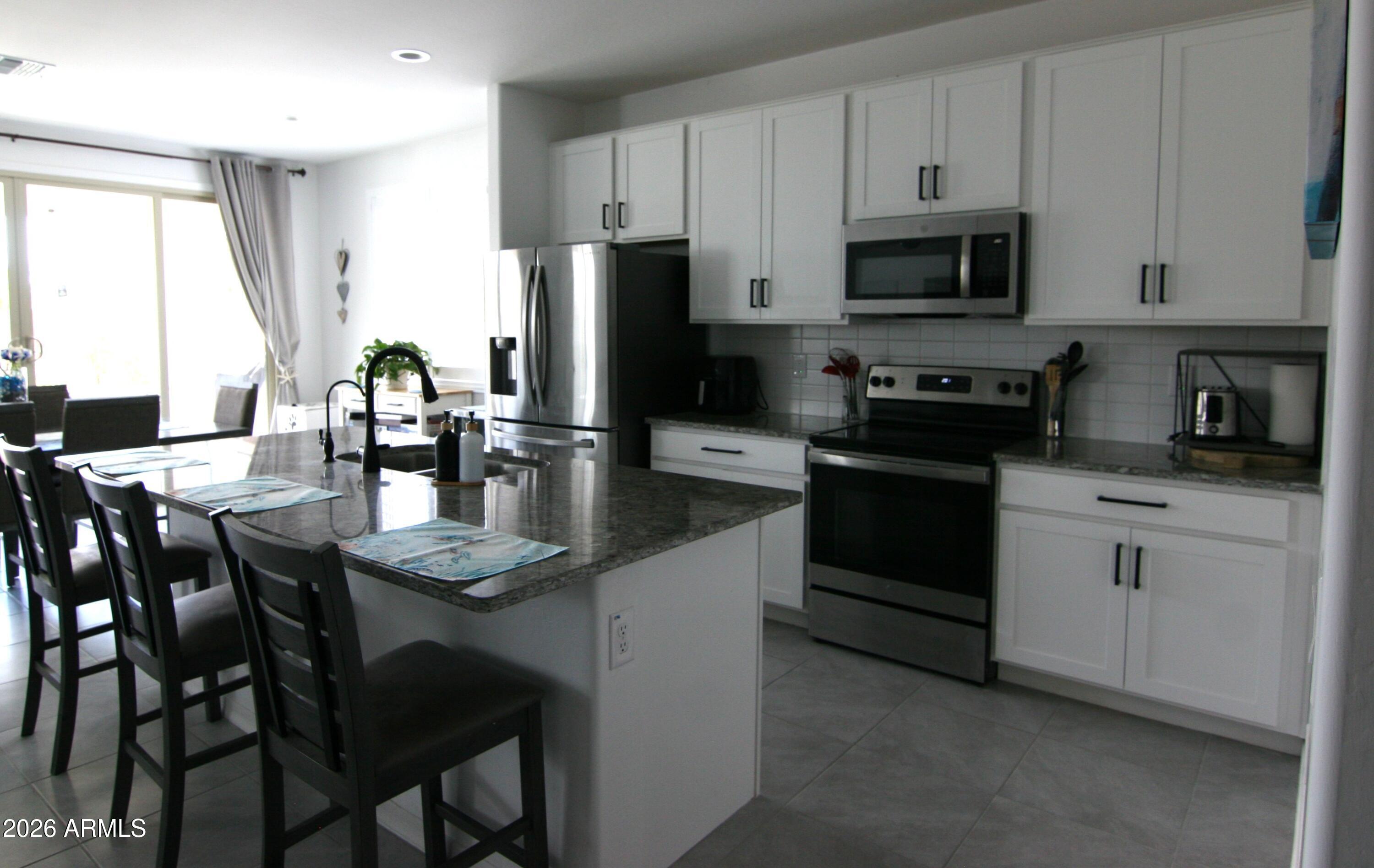 18487 West Ipswitch Way Surprise, AZ 85374 - Photo 2 of 36 a kitchen with stainless steel appliances granite countertop a stove a sink a microwave a refrigerator and white cabinets