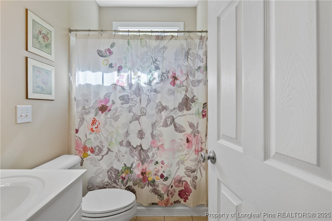 383 Falling Water Road Spring Lake, NC 28390 - Photo 28 of 33 a white toilet sitting next to a shower curtain