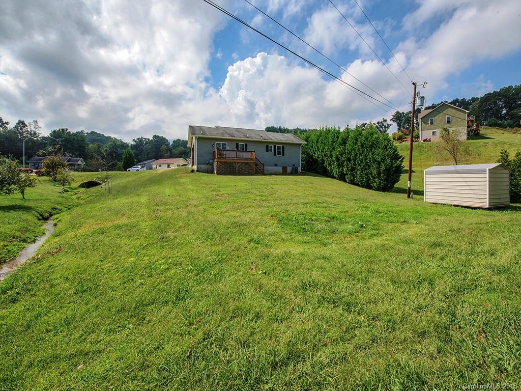 54 Barefoot Ridge Clyde, NC 28721 - Photo 3 of 24 a yellow swimming pool is in the garden with a building in the background