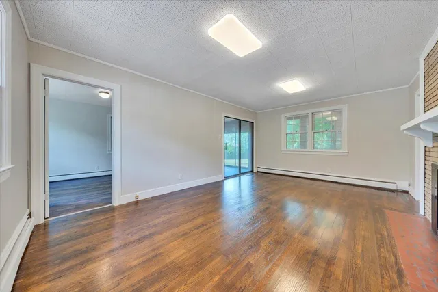 an empty room with wooden floor fireplace and windows