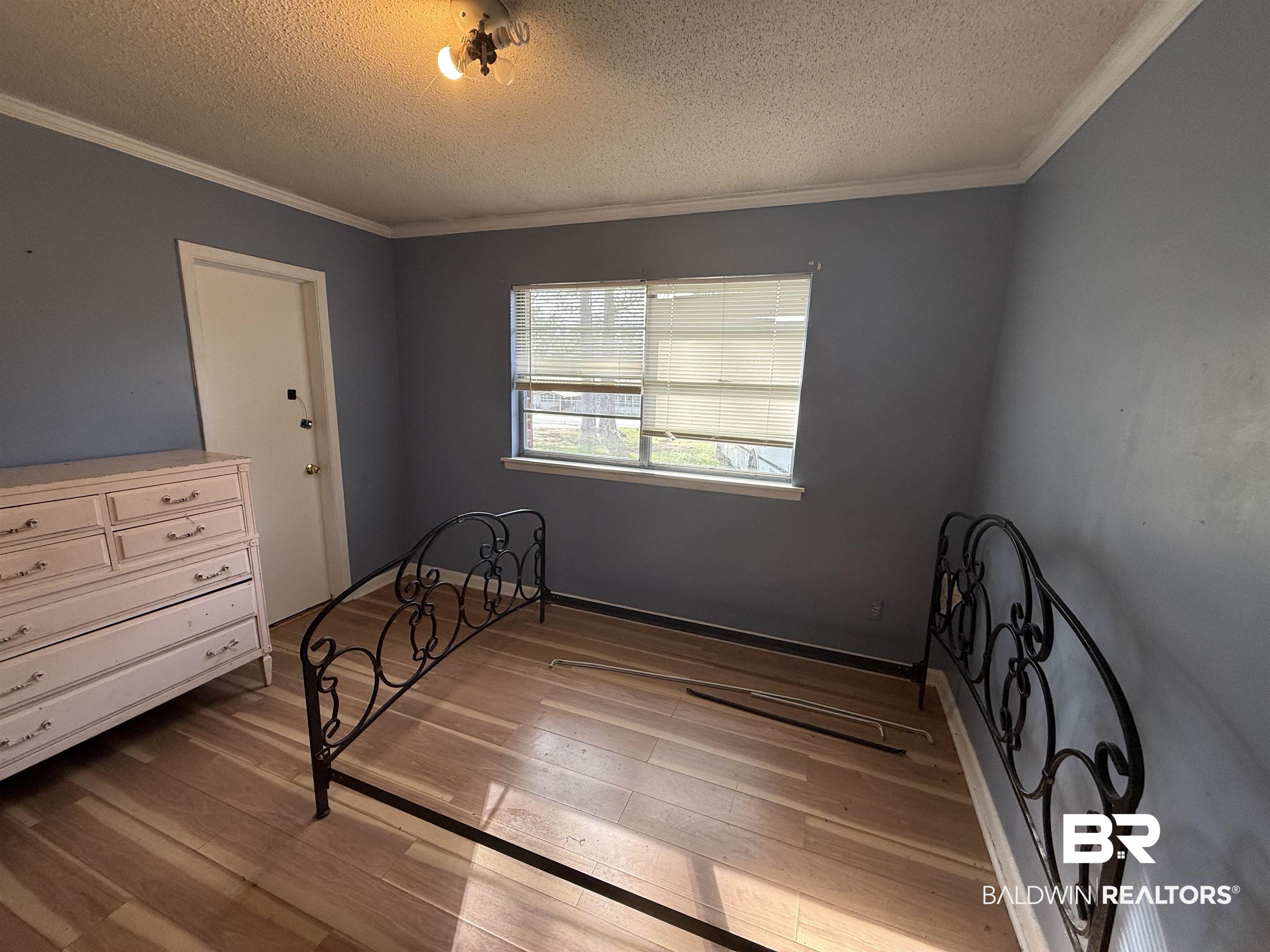 2807 Pea Ridge Road Brewton, AL 36426 - Photo 11 of 12 Bedroom featuring light wood finished floors, a textured ceiling, and ornamental molding