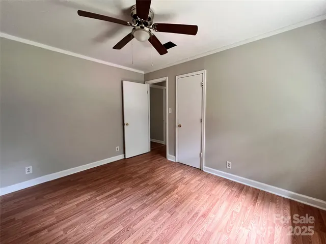 an empty room with wooden floor ceiling fan and windows