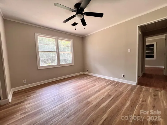 a view of empty room with wooden floor and fan