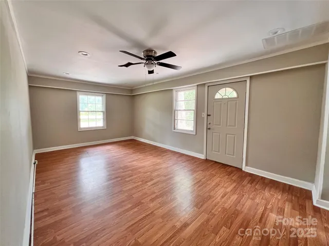 a view of empty room with wooden floor and fan