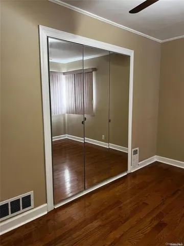 an empty room with wooden floor & closet area