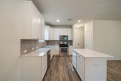 a kitchen with kitchen island granite countertop a stove sink and cabinets