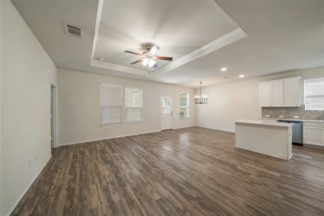 a view of an empty room with window and wooden floor