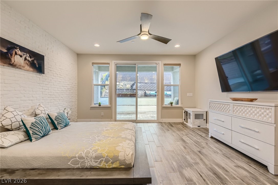 4631 Amazing View Street Las Vegas, NV 89129 - Photo 10 of 33 A comfortable bedroom with a textured white brick wall and wide sliding glass doors that open to the outside.
