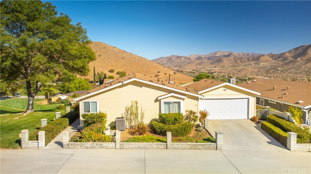 33105 Santiago Road, Unit 118 Acton, CA 93510 - Photo 1 of 1 a view of a white house with a large windows and a yard with plants and large trees