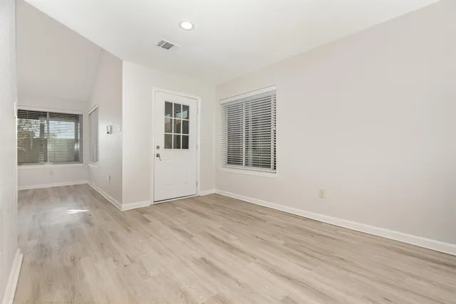 an empty room with wooden floor and windows