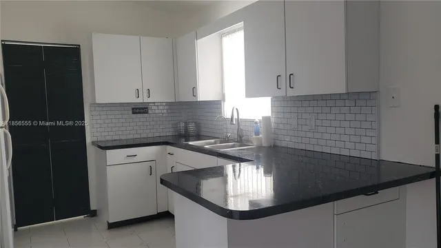 a kitchen with granite countertop a sink a stove and cabinets
