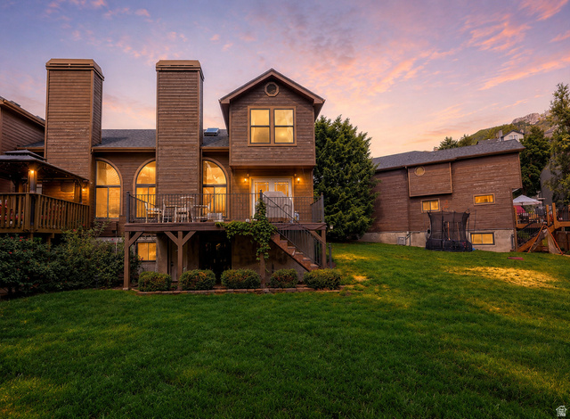 3104 East High Danish Road Sandy, UT 84093 - Photo 35 of 36 Rear exterior featuring a spacious lawn, multiple elevated decks, a wood-sided facade, and arched windows