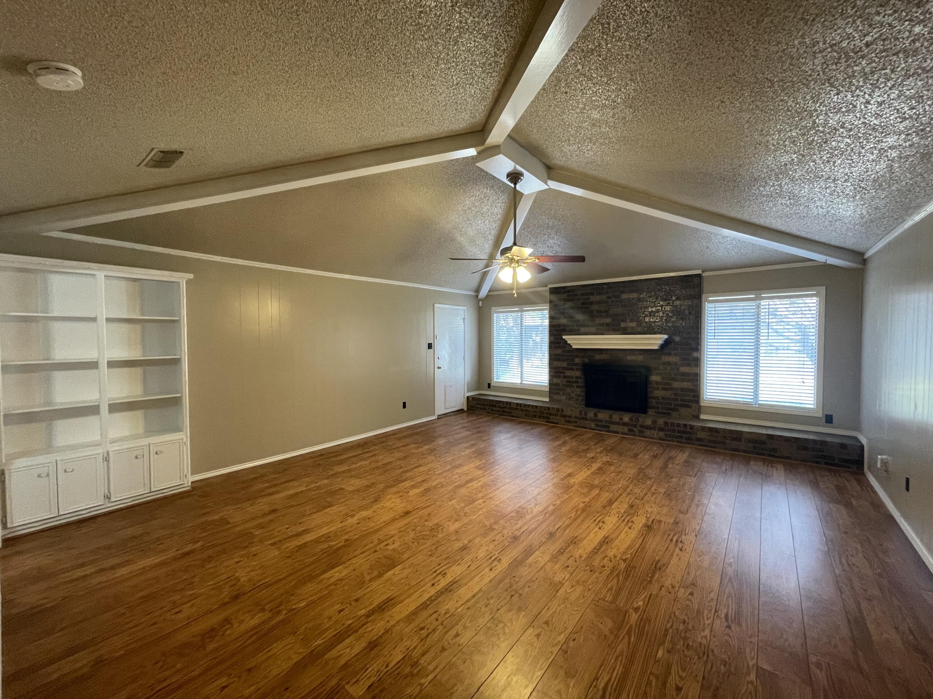 4434 78th Street Lubbock, TX 79424 - Photo 2 of 11 an empty room with wooden floor and windows