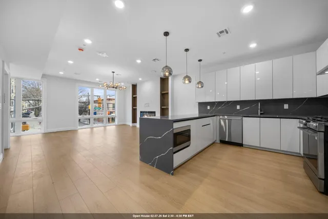 a large kitchen with stainless steel appliances a large counter top a stove a refrigerator and a sink