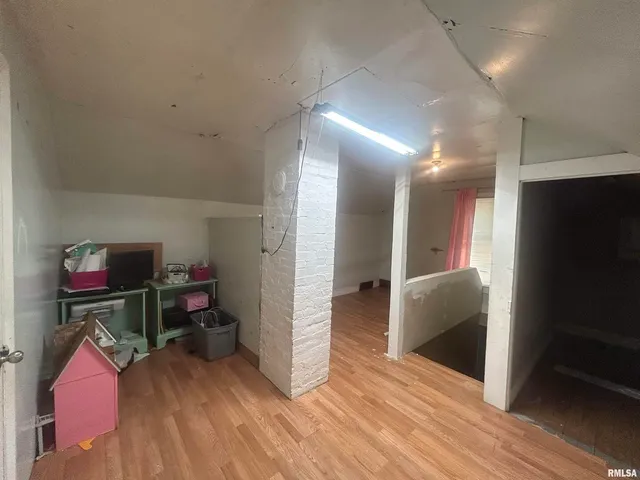 a view of a hallway to room with wooden floor and furniture