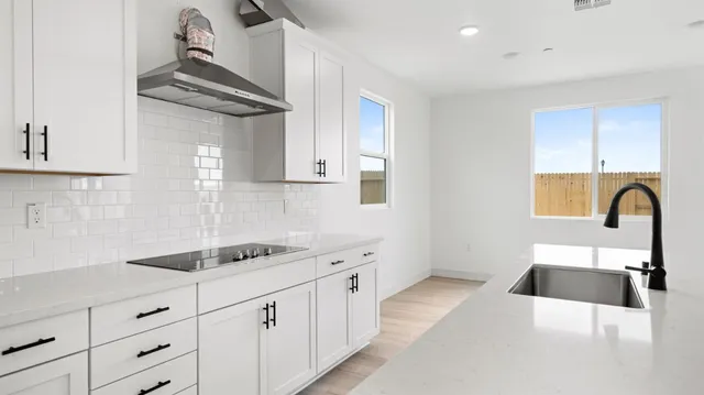 a kitchen with white cabinets a sink and dishwasher