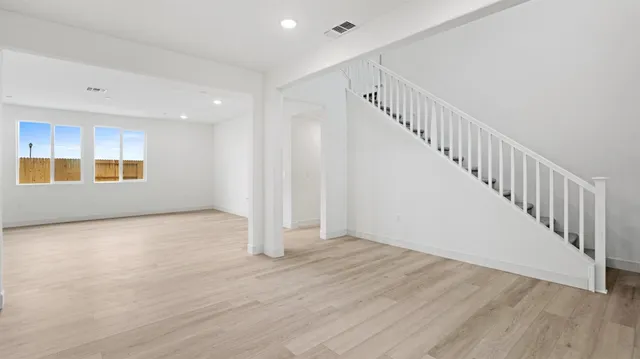 a view of an empty room with wooden floor and stairs