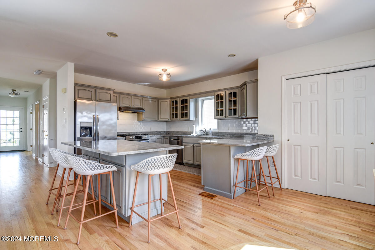 212 Philadelphia Avenue Point Pleasant Beach, NJ 08742 - Photo 11 of 31 a kitchen with stainless steel appliances granite countertop a stove top oven a sink dishwasher a dining table and chairs with wooden floor