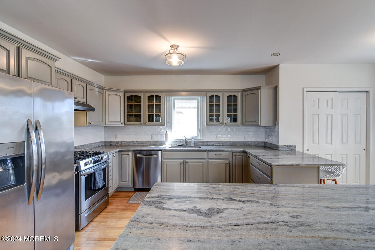 212 Philadelphia Avenue Point Pleasant Beach, NJ 08742 - Photo 15 of 31 a large kitchen with stainless steel appliances granite countertop a stove a sink dishwasher a refrigerator and white cabinets with wooden floor