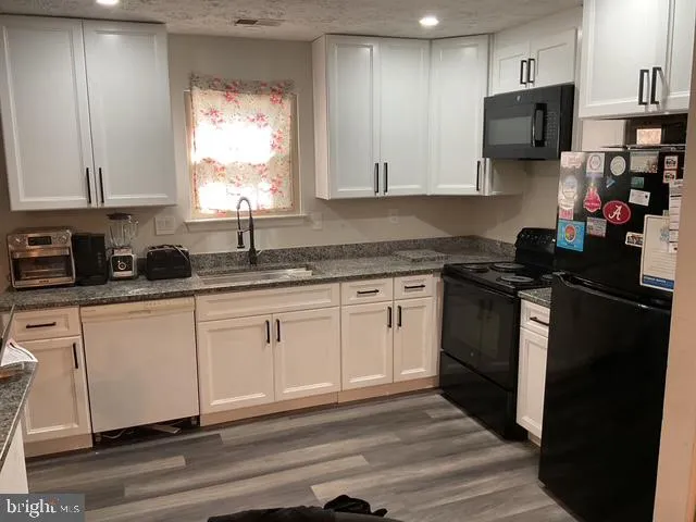 a kitchen with granite countertop a sink cabinets and stainless steel appliances