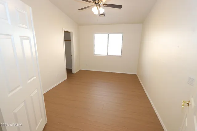a view of a room with wooden floor and a ceiling fan