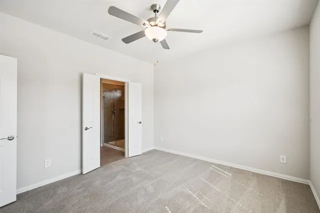 an empty room with closet and a ceiling fan