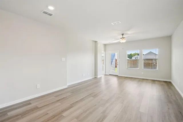an empty room with wooden floor chandelier and windows