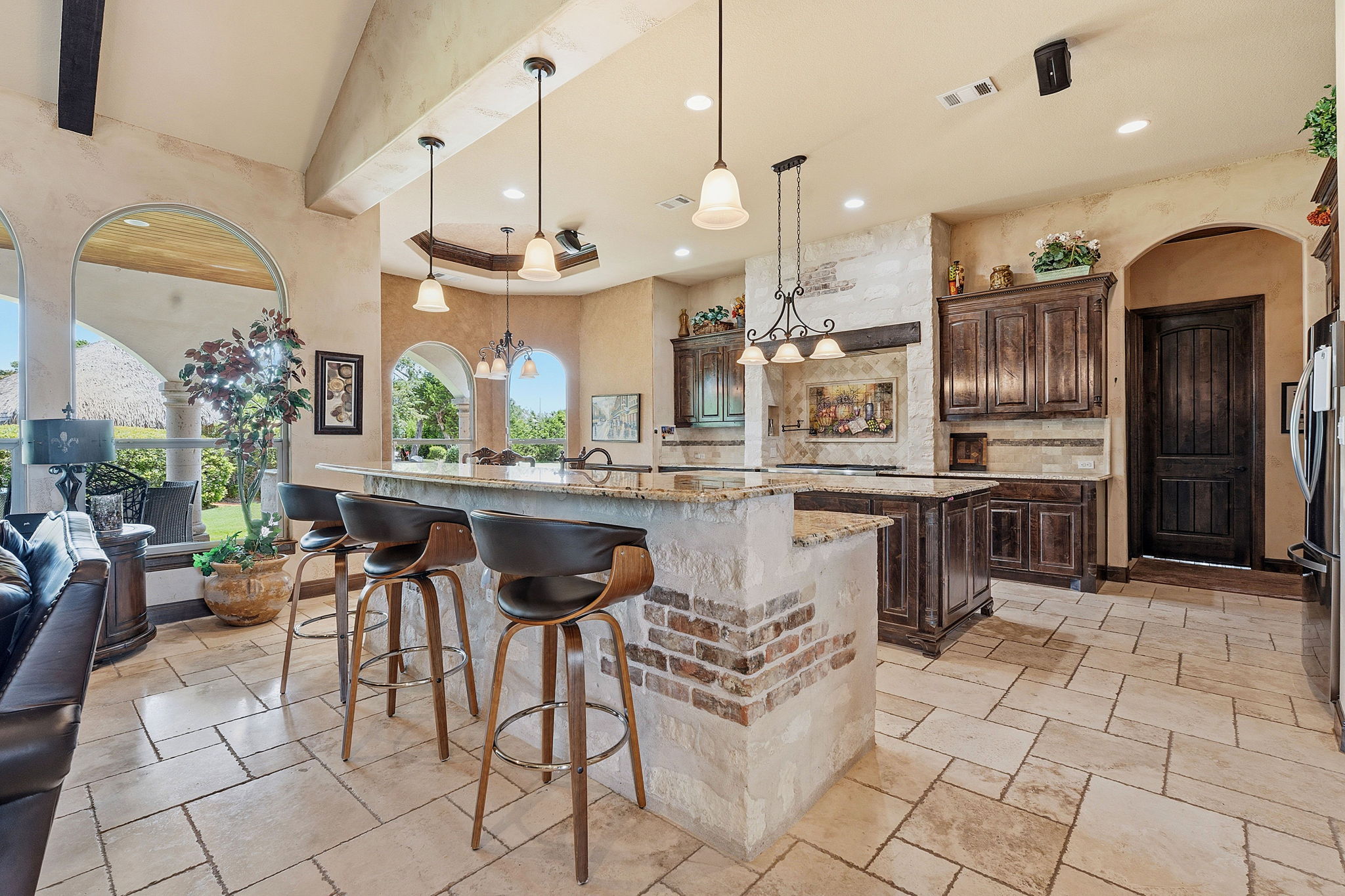816 Brave Face Street Leander, TX 78641 - Photo 5 of 40 Stone flooring and elegant arched windows define this spacious open-concept kitchen, perfect for entertaining.