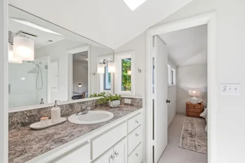 a en suite bathroom with a granite countertop sink and mirror