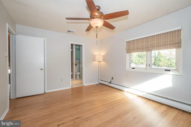 an empty room with wooden floor chandelier fan and windows