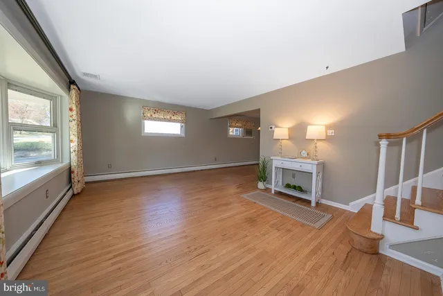 wooden floor in an empty room with a fireplace and a window