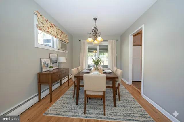 a dining room with wooden floor a chandelier a wooden table and chairs