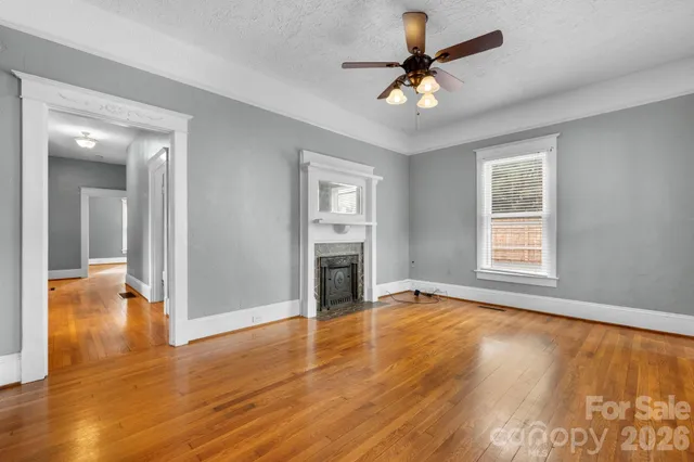 a view of an empty room with window and wooden floor