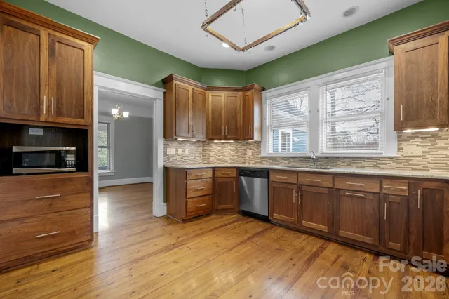 a kitchen with stainless steel appliances granite countertop wooden cabinets a oven and granite counter tops with a large window