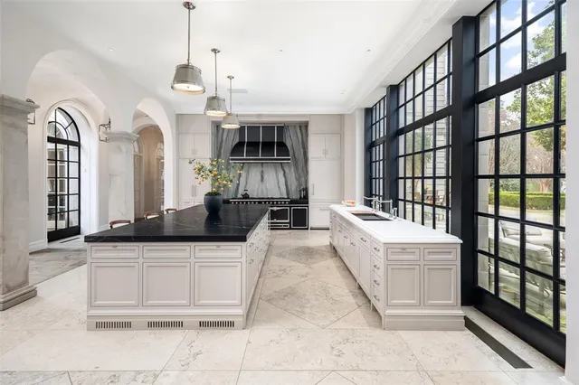 a large white kitchen with granite countertop a large counter top and white cabinets
