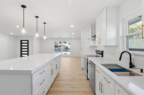 a large kitchen with stainless steel appliances kitchen island a large island a sink a stove and a wooden floors