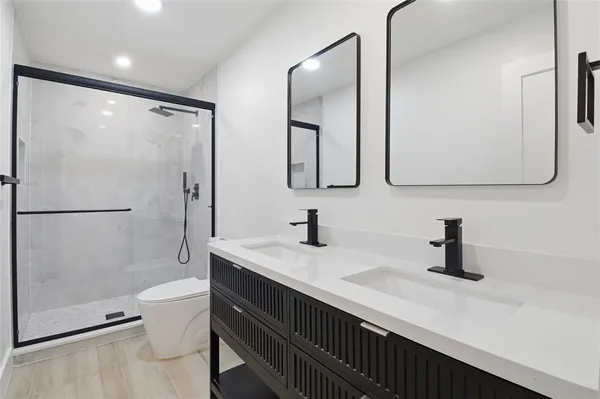a bathroom with a sink a toilet a mirror and shower