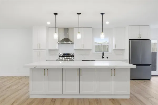 a kitchen with stainless steel appliances granite countertop a sink a stove a refrigerator and island with wooden floor